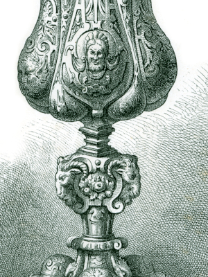 Close-up of the engraved silver cup, showing the sculpted horned heads and intricate decorative details.